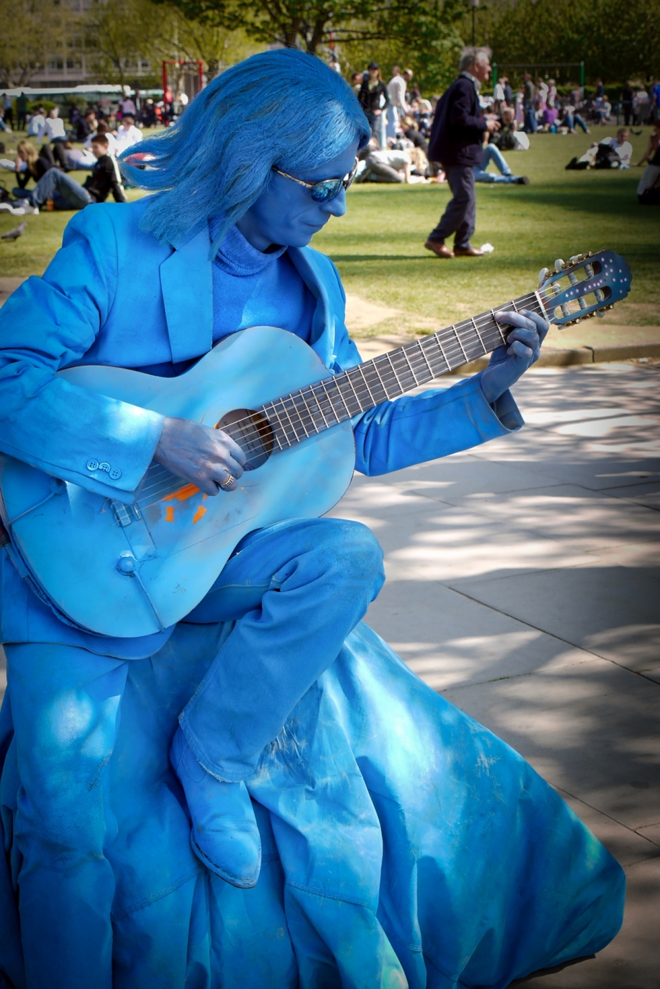石头上穿蓝色衣服弹吉他的行为艺术家