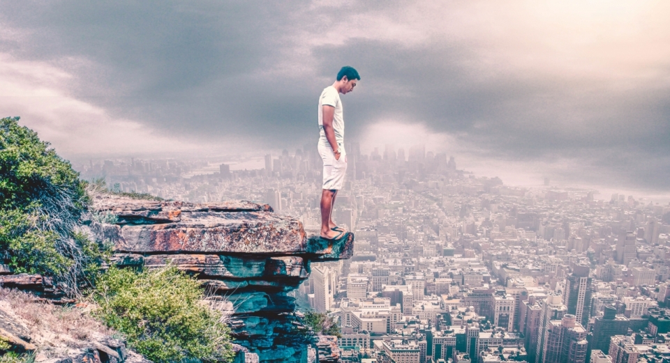 一名男士正站在悬崖边,俯瞰着山下万千的城市建筑,此时此刻他就像一个