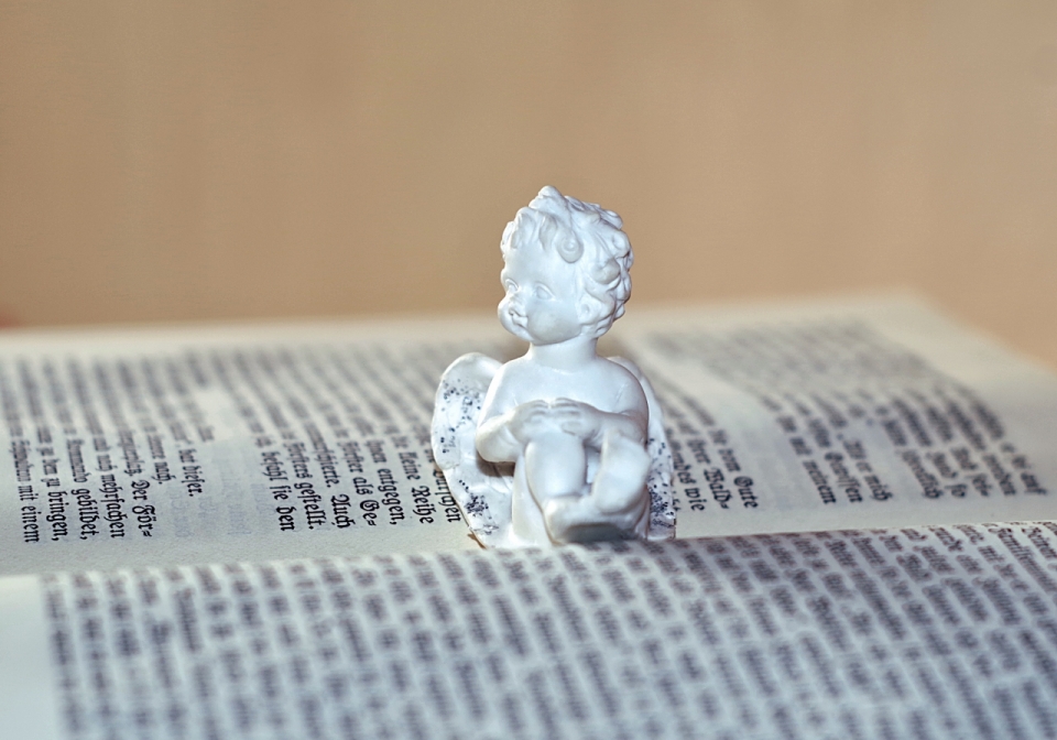 坐在书本上的白色小天使雕塑