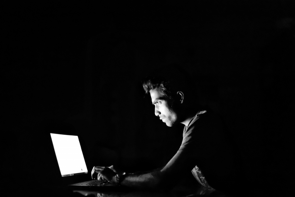 黑色背景在电脑前工作的男人