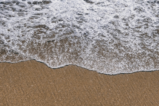 黄色海滩上白色浪花水面摄影