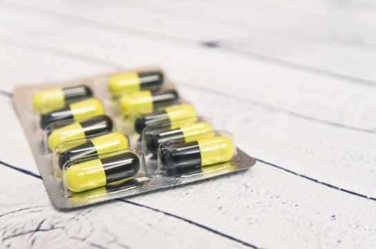 白色桌子上黄色和黑色相间未拆封的药丸