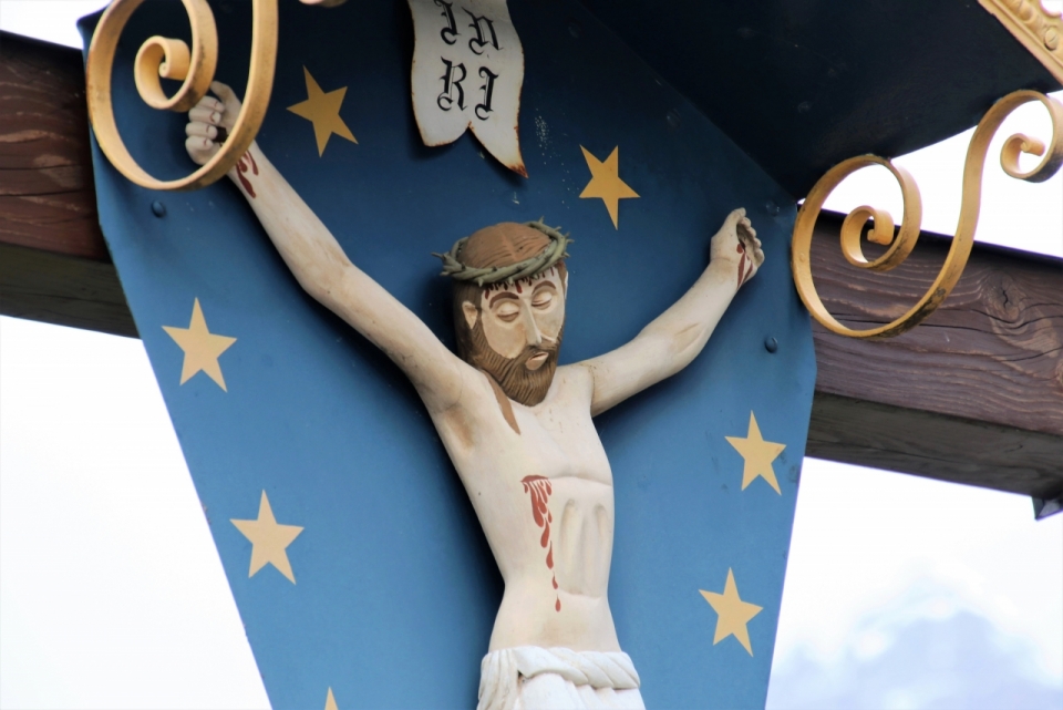 蓝天下十字架上耶稣受难彩色古老历史雕像