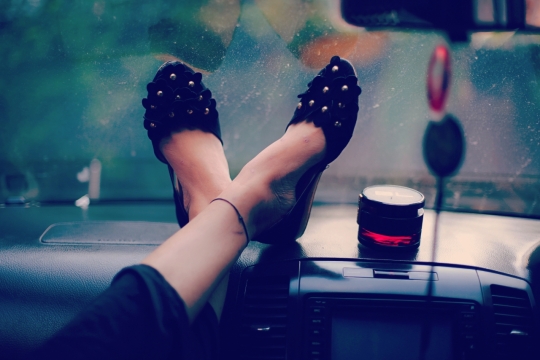 城市马路轿车内部黑色鞋子翘腿女性