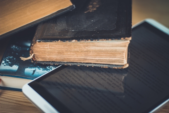 桌面上堆叠的旧书本和电子书
