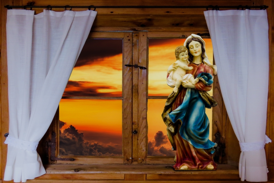 木窗台上圣母雕像和窗外美丽晚霞