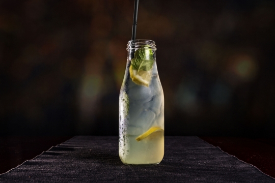 虚化背景木桌玻璃瓶新鲜柠檬切片果汁