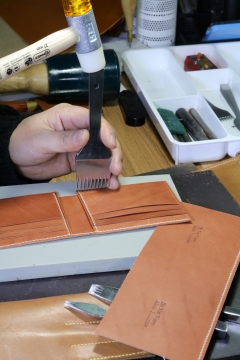 室内木制桌面皮革钱包手工打孔男性手部特写