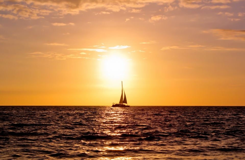 夕阳时分,太阳慢慢向西方落去,阳光染红了天空与大海,一艘帆船孤独的