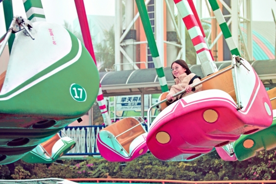 坐城市游乐园彩色设施快乐长发女性