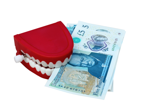 白色背景假牙模型咬蓝色英国纸币