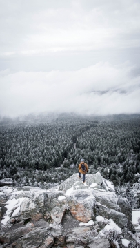 雪山悬崖上登山者眺望林海