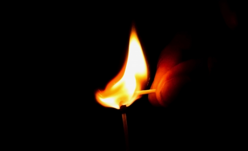 黑暗中燃烧的火柴正在点燃另一根火柴
