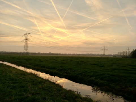 天边落日晚霞照耀高压线铁架天空飞机航线飞机尾气图