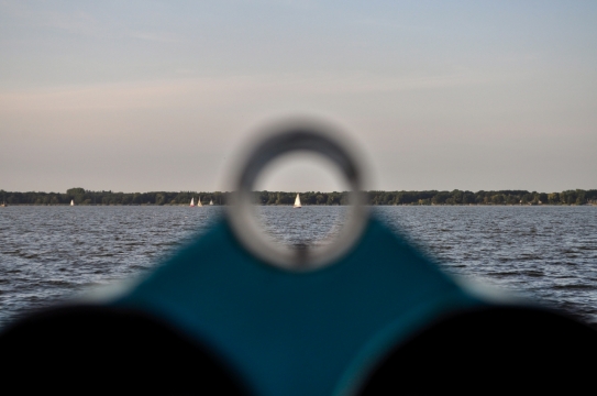 用管观察对岸远景海面上的帆船