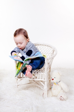 白色背景椅子上看杂志的小宝宝