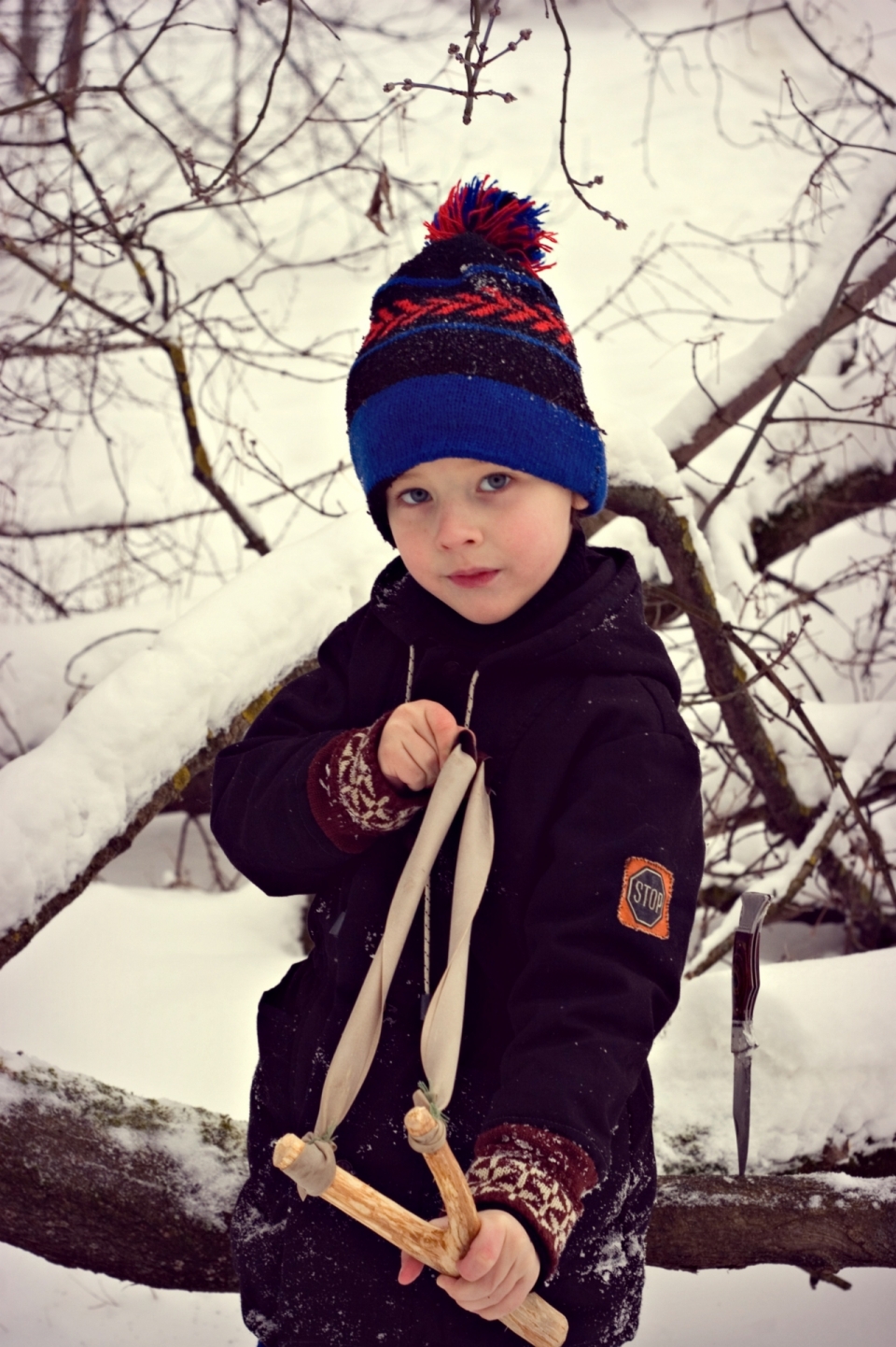 寒冷冬天雪后户外拿弹弓戴针织帽男孩