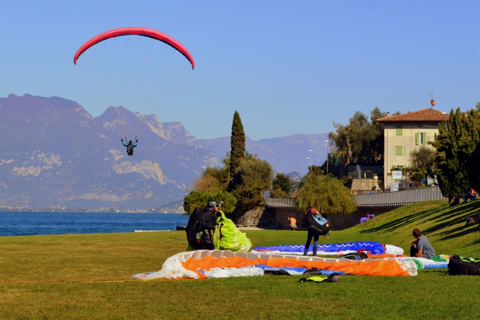 即将降落在湖边草坪上的滑翔伞极限运动员