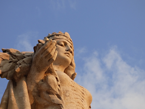 仰拍蓝色天空阳光下古老艺术石质雕像