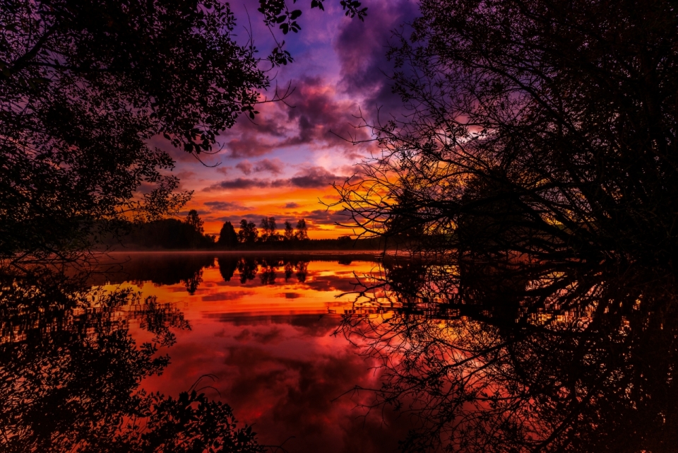 夕阳红色晚霞天空白云树木倒映在湖泊上