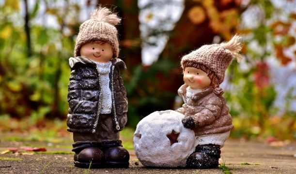 背景虚化树木前堆雪球的娃娃玩偶