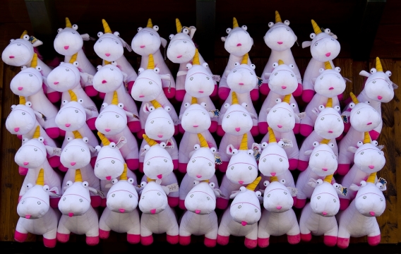 黑色背景前一排排整齐的独角兽毛绒玩具