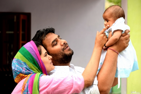 正举着孩子的父亲与逗孩子的母亲合影