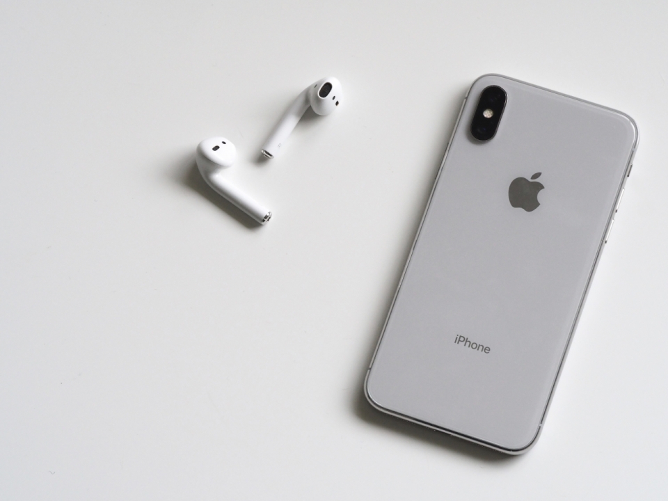桌面灰色iPhone手机白色蓝牙耳机