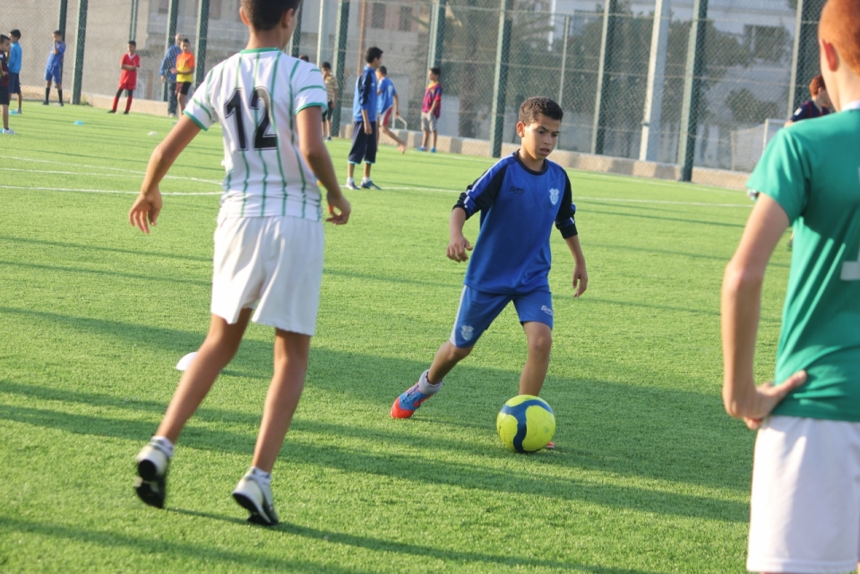 绿茵足球场上正在练习足球的小男孩