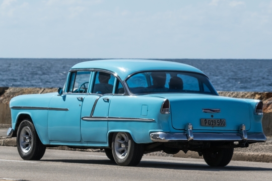 自然湖泊边城市马路行驶蓝色轿车