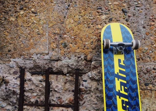 破损墙壁边靠立蓝色滑板静物摄影