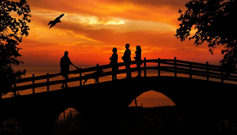夕阳下站在桥上的四人一狗剪影