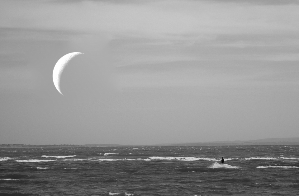 夜晚悬挂弯月海面冲浪人物夜景