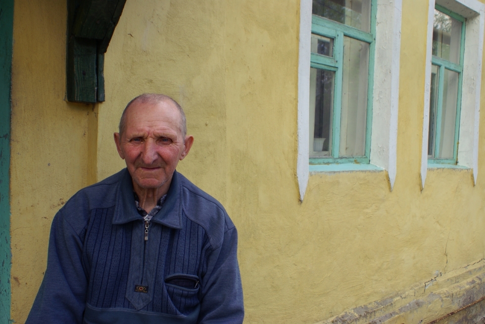 俄罗斯乡村黄色建筑前老年男性