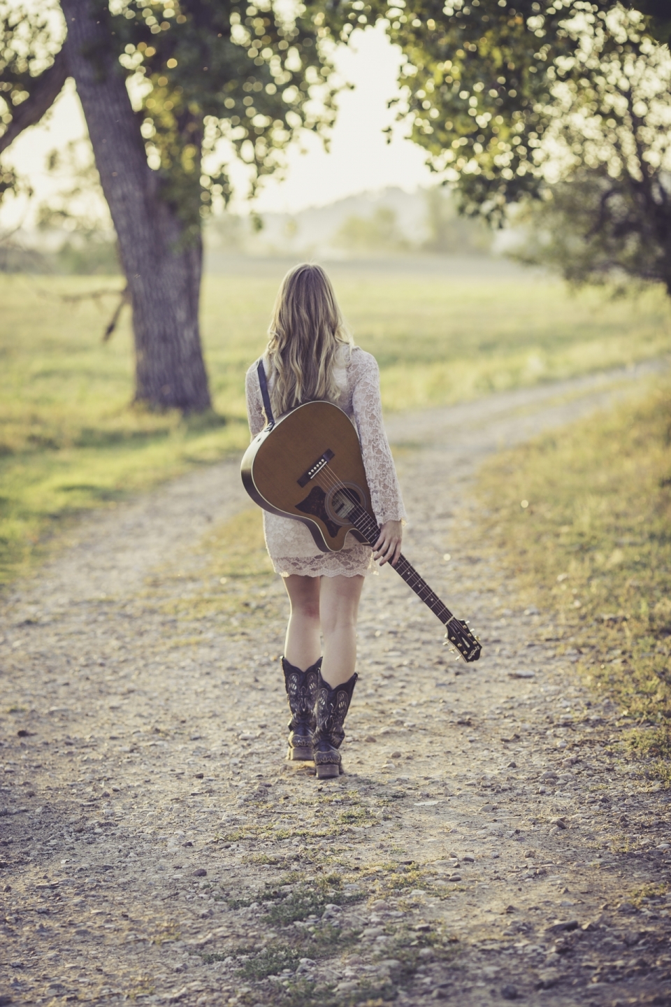背着吉他的金色长发美女在林间漫步