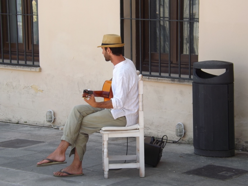 街边坐在白色椅子上弹吉他的男子