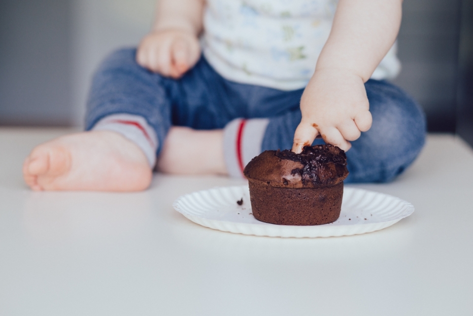 坐地面儿童手指戳盘子中巧克力蛋糕