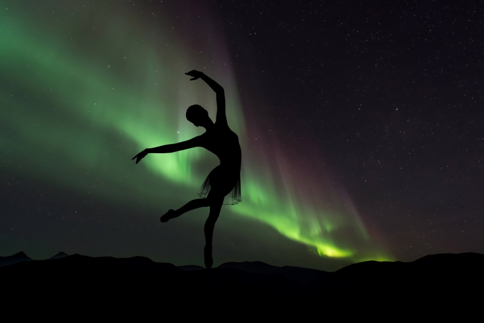 黑暗中绿色的极光下跳芭蕾舞的舞女