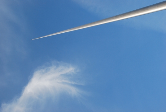 蓝色天空白云下直插天际的旗杆