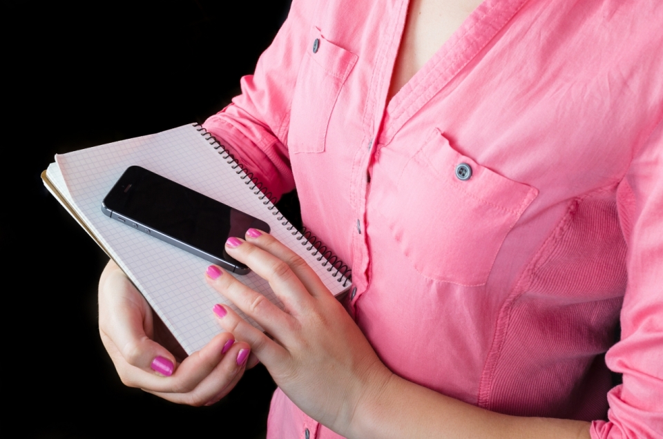 黑色背景商务着粉色衬衫女性持手机和笔记本