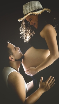 男子将下巴放在怀孕妻子的肚子上