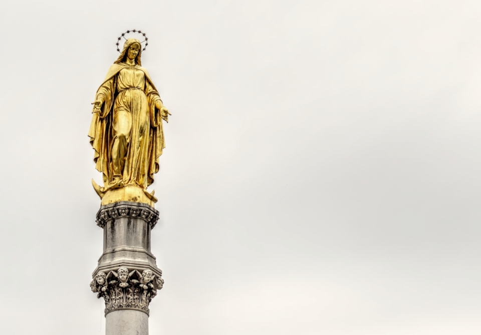 天空下高台上金色的圣母雕像