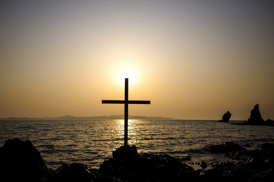 日出时海边十字架的逆光摄影