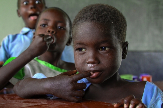 室内木桌前舔舐手指非洲黑人男孩