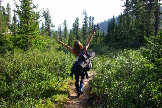 背包走在绿色林间小道女子背影摄影