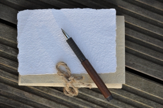 木质桌子上的白色纸黄色纸和笔文艺摄影