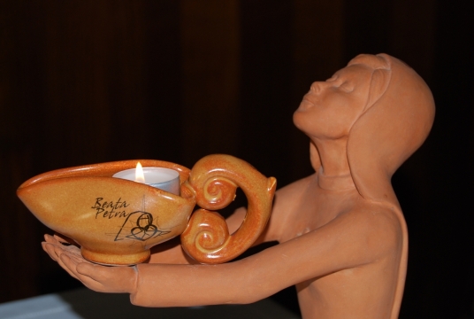 昏暗室内捧蜡烛祈祷修女石质塑像