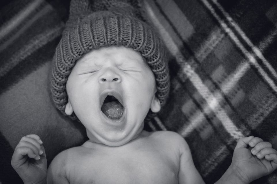 带着帽子睡在毛毯上正在打哈欠婴儿
