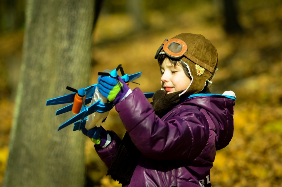 树林背景前戴飞行帽那飞机模型的小男孩