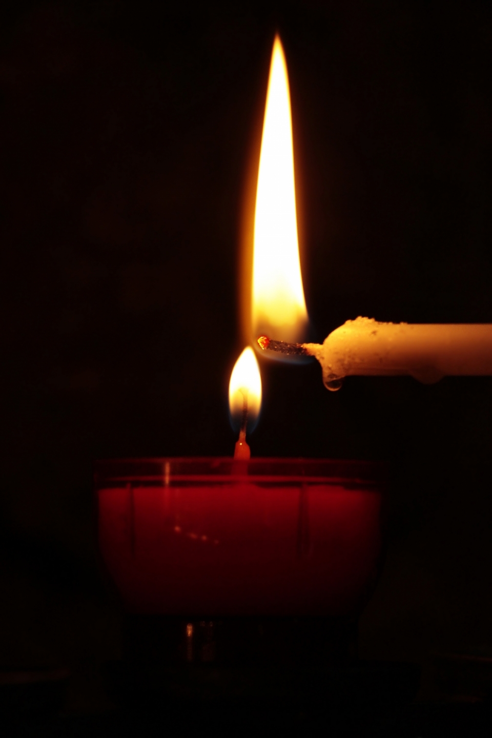 黑色背景下白色蜡烛点燃了红色蜡烛